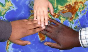 Handen van kinderen op een wereldkaart